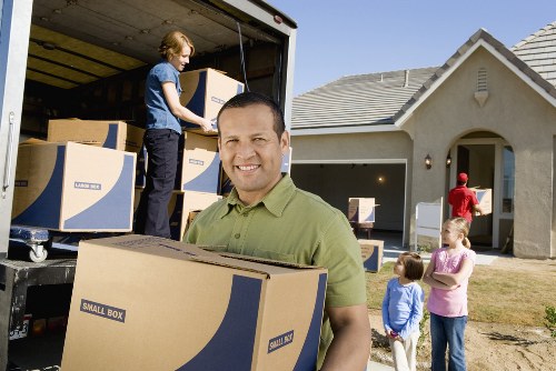 Movers carrying boxes through a suburban Maryland home